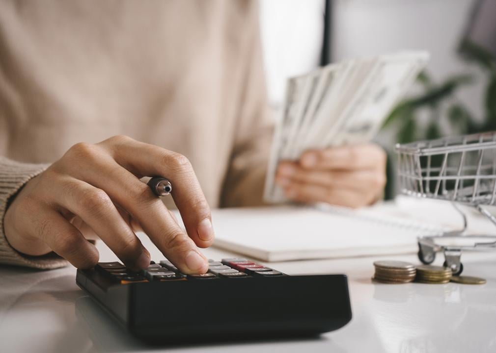 A woman budgeting using a calculator and counting money.